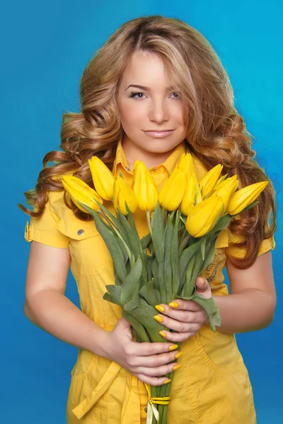 Belle fille avec des fleurs de tulipe sur bleu. Modèle de beauté femme — Photo