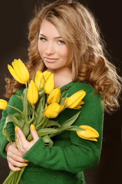 Attraktives Teenager-Mädchen mit Tulpen in den Händen über schwarzem Hintergrund — Stockfoto