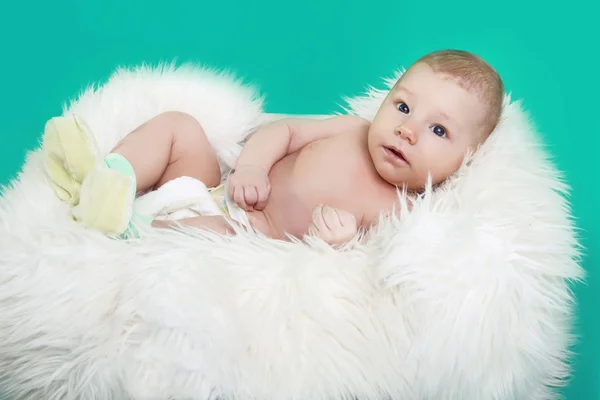 Close-up of lovely baby boy resting on fur over green — Stock Photo, Image