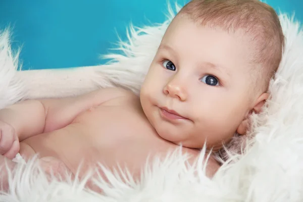 Primer plano de la dulce carita de bebé, mirando hacia arriba, sobre ba azul — Foto de Stock