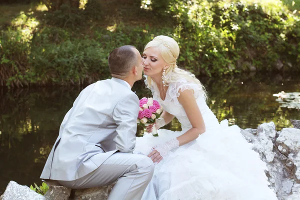 Nevěsta a ženich objetí a polibky na jejich svatební den — Stock fotografie