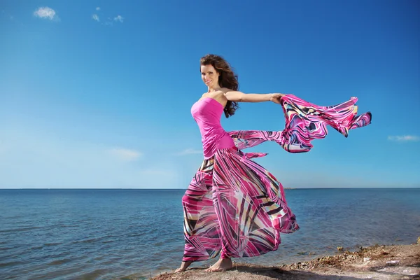 Beautiful young woman in blowing dress opened her hands with del — Stock Photo, Image