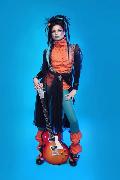 Rockgirl posiert mit E-Gitarre isoliert auf blauem Hintergrund — Stockfoto