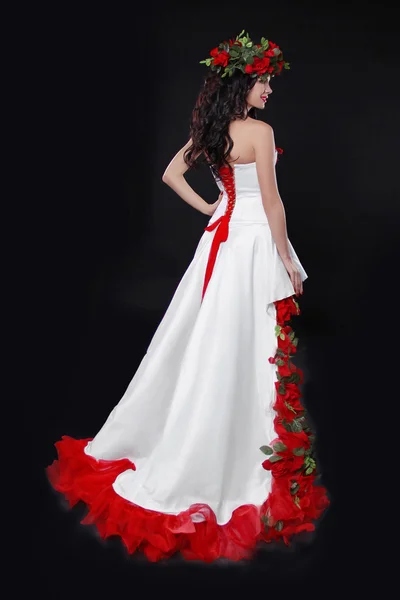 Fashion brunette model posing in white dress with red roses skir — Stock Photo, Image