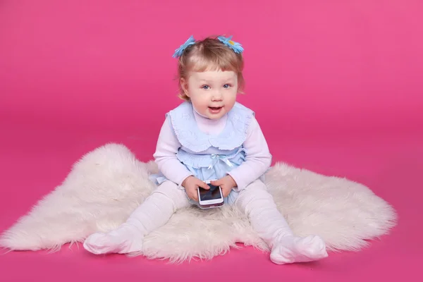 Vicces kis lány, játék-val mozgatható telefon mint rózsaszín háttér — Stock Fotó