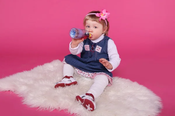 Portret van grappige kleine meisje drinkwater, zittend op bont over — Stockfoto