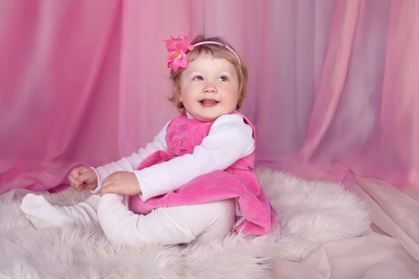 Happy smiling funny little girl resting on bed over pink draper — Stock Photo, Image