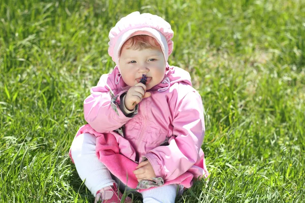 Porträtt av glad liten flicka vilar på grönt gräs i parken — Stockfoto