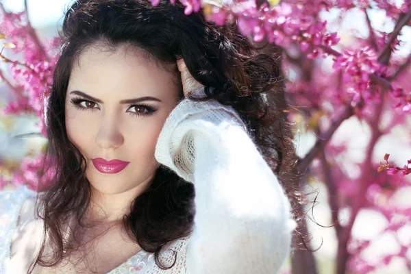 Beautiful brunette woman over pink brunch of tree, outdoors port — Stock Photo, Image