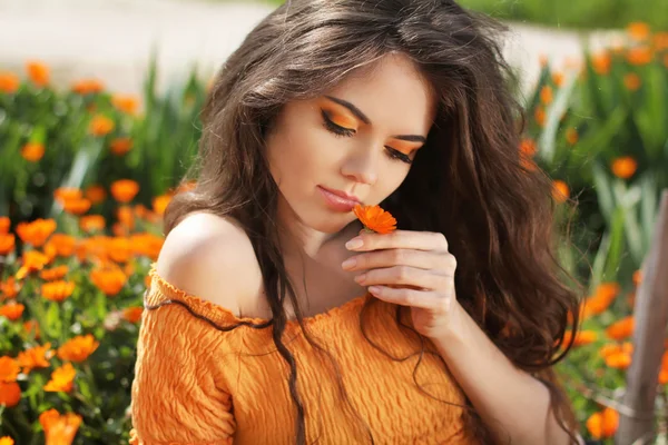 Beautiful brunette woman with colored makeup smelling flower, ov — Stock Photo, Image