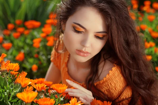 Young woman outdoors portrait over orange marigold flowers — Stok fotoğraf