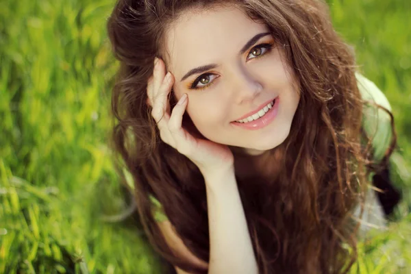 Menina sorridente feliz descansando na grama verde, retrato ao ar livre — Fotografia de Stock