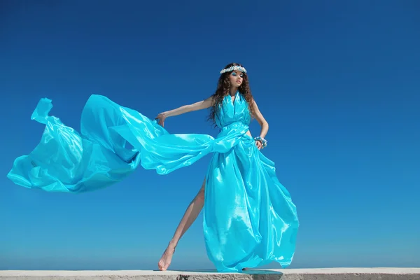 Femme modèle de mode avec robe soufflante sur le ciel bleu, à l'extérieur — Photo