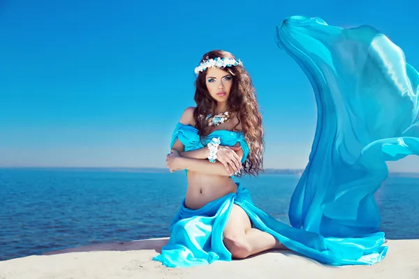 Mooie vrouw model poseren in jurk waait over blauwe hemel — Stockfoto