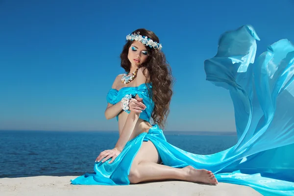 Hermosa mujer modelo en soplado vestido volando descansando sobre azul — Foto de Stock
