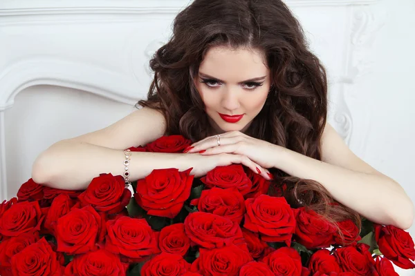 Beautiful brunette woman with red roses bouquet of flowers at at in — стоковое фото