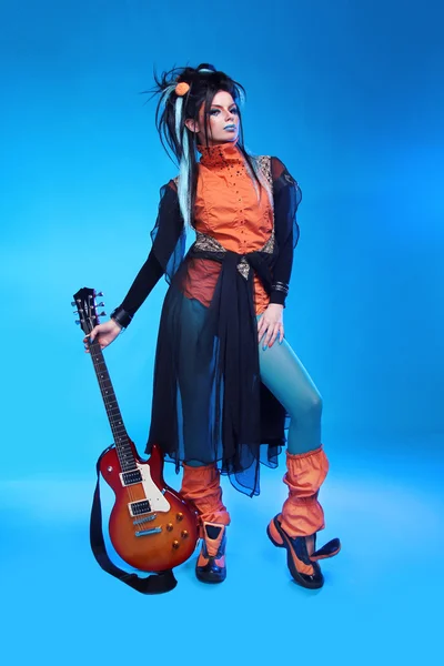 Рок-девушка позирует с электрогитарой на голубом бэкграунде — стоковое фото