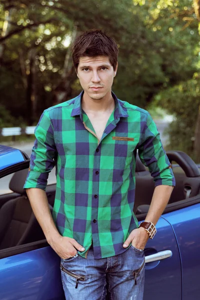 Hombre guapo con ropa casual posando cerca de su coche, al aire libre p — Foto de Stock