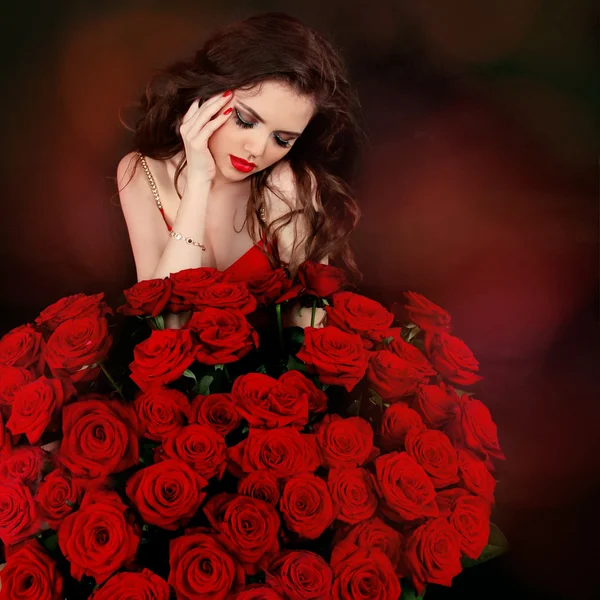 Young beautiful woman with red roses bouquet over flowers — Stock Photo, Image