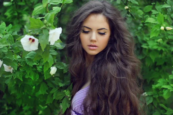 Mooie vrouw met lang krullend haar. openlucht portret op groen — Stockfoto