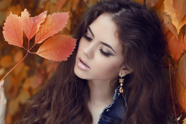 Le plaisir. Jeune femme brune souriante heureuse sur les feuilles d'automne — Photo