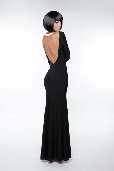 Brunette vrouw met sexy terug in zwarte lange jurk die zich voordeed bij stud — Stockfoto