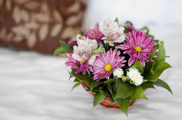 Belo buquê de flores coloridas em cesta contra a cama — Fotografia de Stock