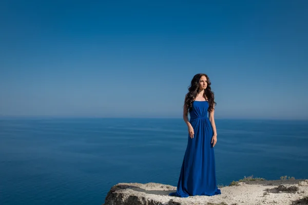 Summer portrait. Beautiful woman standing on a cliff over blue s — Stock Photo, Image