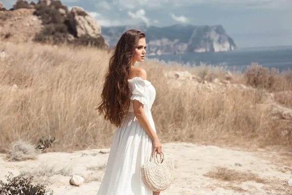 干し草畑で楽しむ手織りのハンドバッグと白いドレスの美しい若い女性の肖像画 自然の美しさ女性 人生を感じるロマンチックな花嫁 — ストック写真