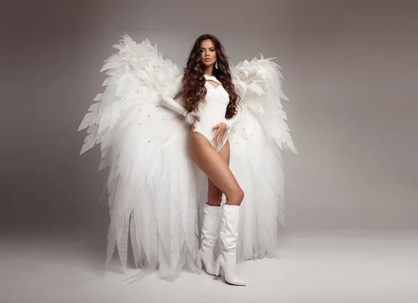 白い翼をポーズでファッション衣装で美しいセクシーな天使モデルのフル長スタジオの肖像画 流行の服で長い波状の髪のスタイルを持つファッショナブルな魅力的なブルネットの女性 — ストック写真