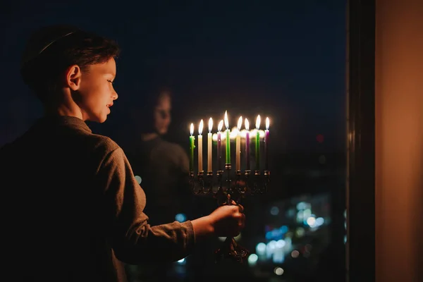 Niño Enciende Menorá Para Janucá Alféizar Ventana Chico Kippah Sentado —  Fotos de Stock