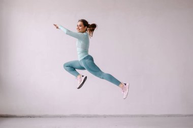 Arka planda spor kıyafetli güzel bir kadının uzun bir portresi var.