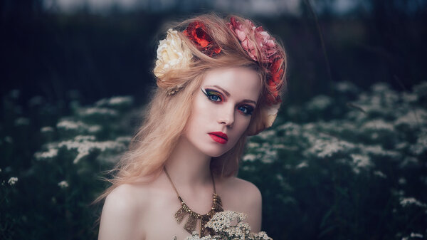 Art fashion portrait of young blond girl with flowers in hair on meadow