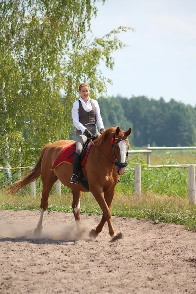 Hermosa joven rubia montando caballo castaño — Foto de Stock