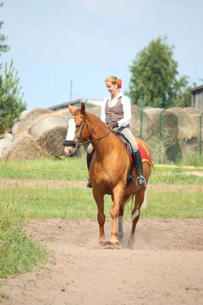 Beautiful young blonde woman riding chestnut horse — Stock Photo, Image