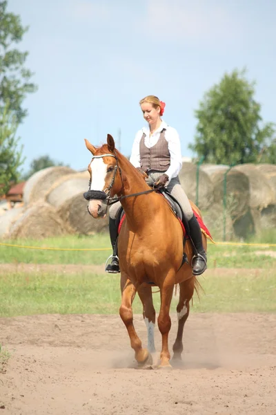 Schöne junge blonde Frau reitet Kastanienpferd — Stockfoto