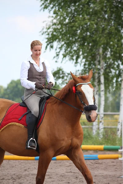 Beautiful young blonde woman riding chestnut horse — Stock Photo, Image