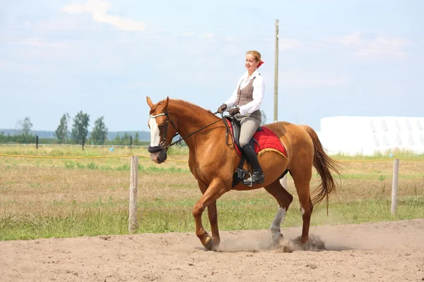 Beautiful young blonde woman riding chestnut horse — Stock Photo, Image