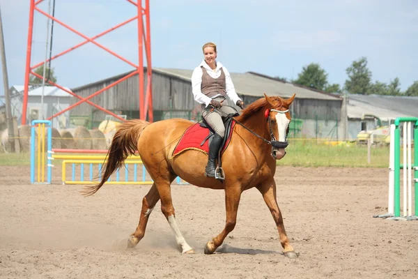 Beautiful young blonde woman riding chestnut horse — Stock Photo, Image