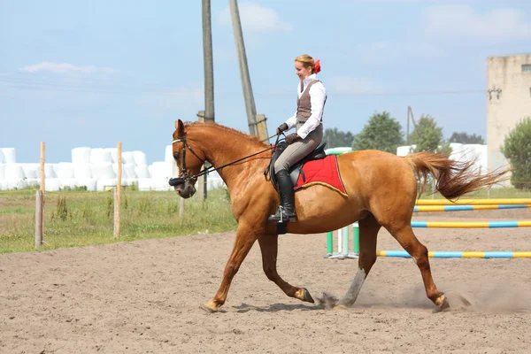 Beautiful young blonde woman riding chestnut horse — Stock Photo, Image