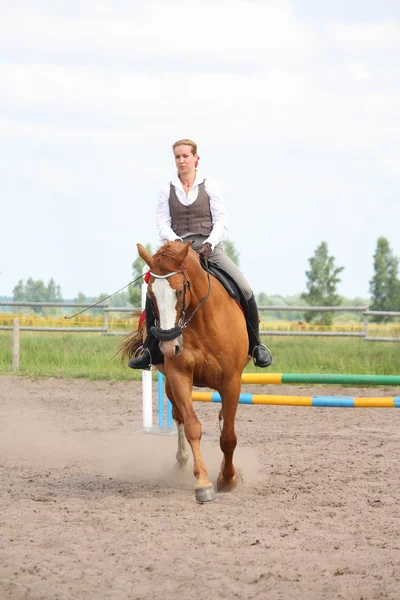 Beautiful young blonde woman riding chestnut horse — Stock Photo, Image