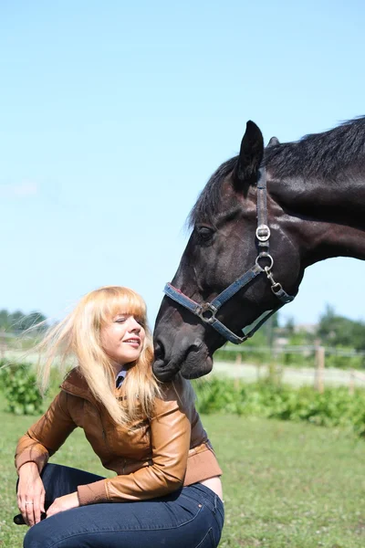 Blond kobieta i czarny koń — Zdjęcie stockowe