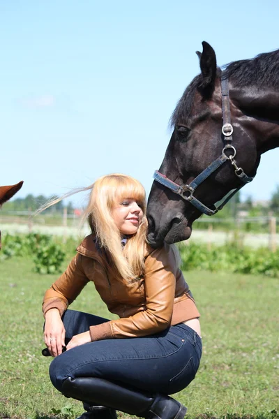 Femme blonde et cheval noir — Photo