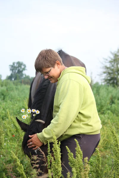 Smiling teenager boy with horses at the field — Stock Photo, Image