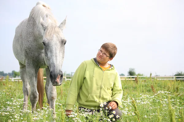 Happy teenager boy and white horse at the field — Stock Photo, Image