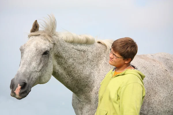 Felice adolescente ragazzo e cavallo bianco al campo — Foto Stock