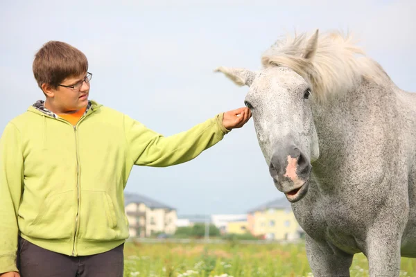 幸せな 10 代の少年と、フィールドでの白い馬 — ストック写真