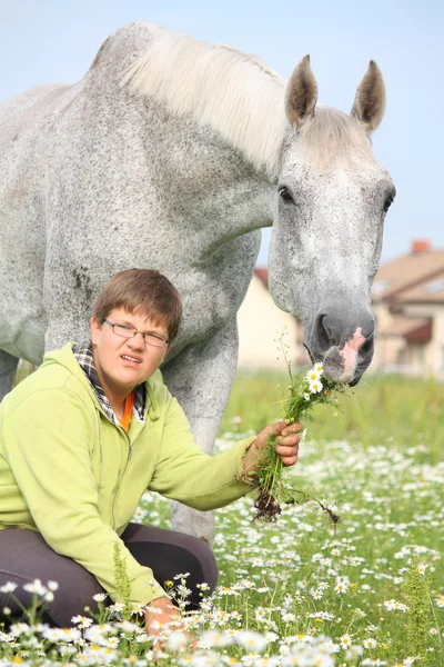 Happy teenager boy and white horse at the field — Stock Photo, Image