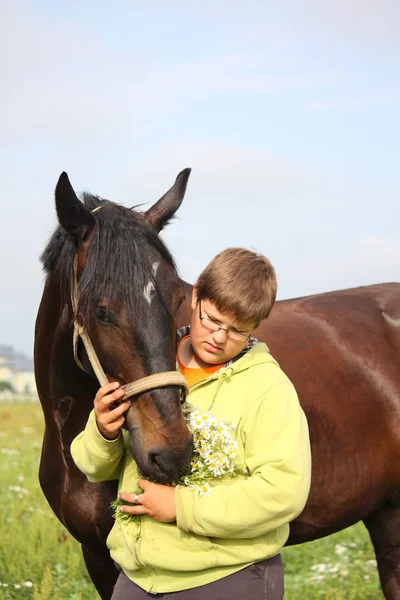 Smiling teenager boy with horses at the field — Stock Photo, Image