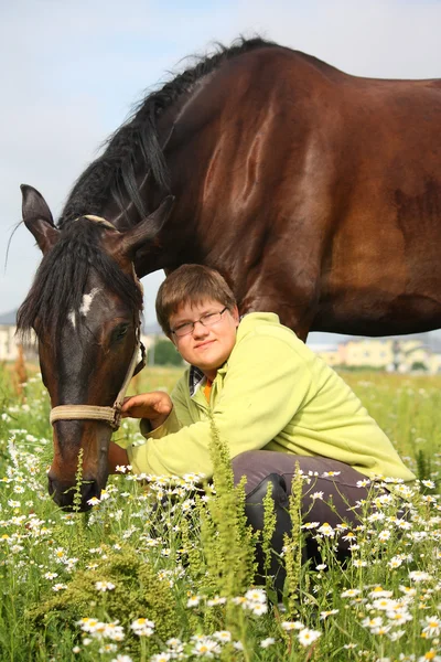 Smiling teenager boy with horses at the field — Stock Photo, Image